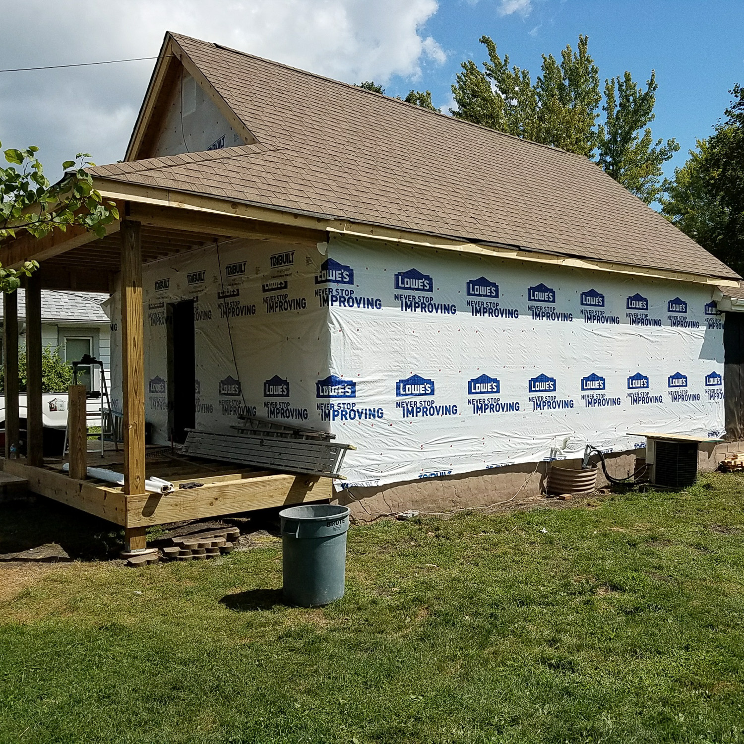 house during wind damage restoration process. House framed, new roof installed, no siding yet, during construction.