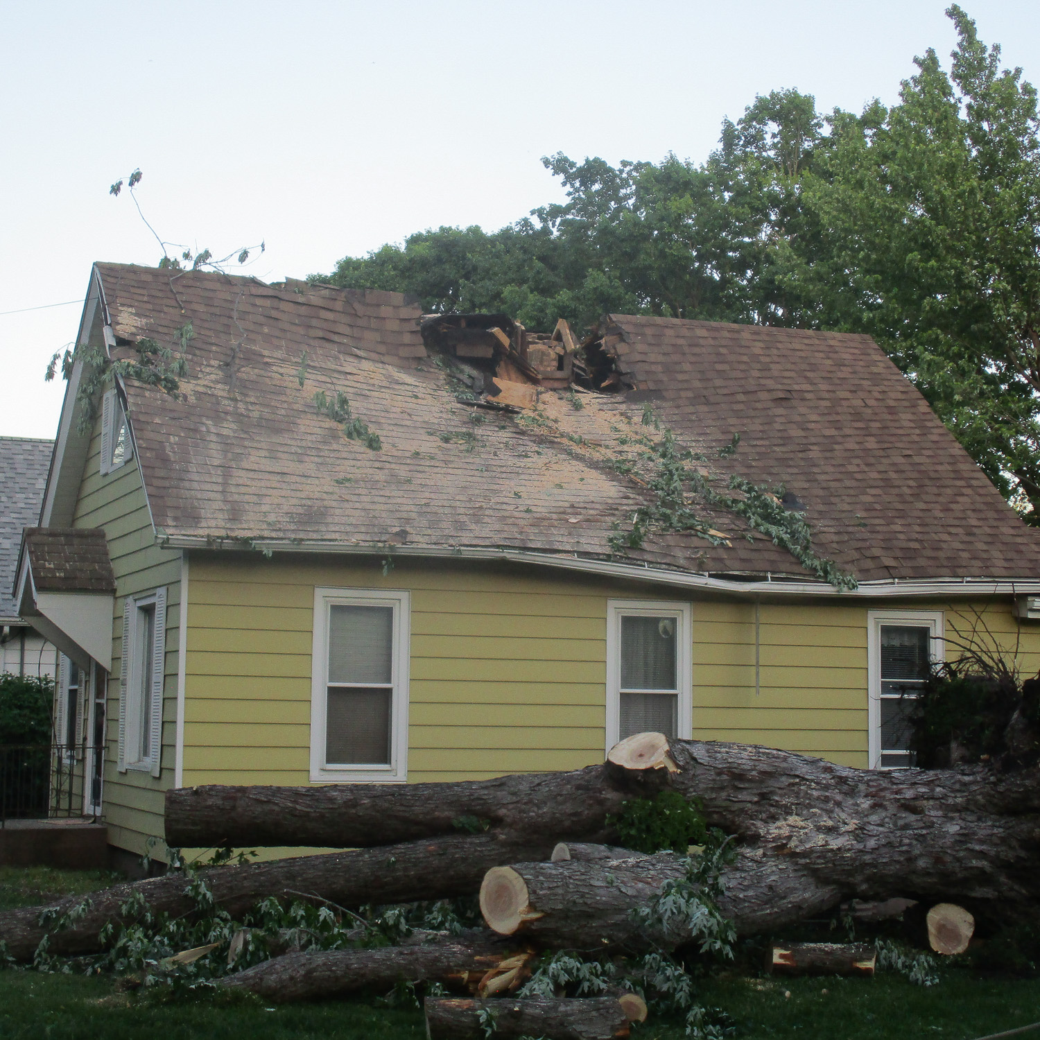 roof damage from fallen tree-large hole in roof from tree impact.